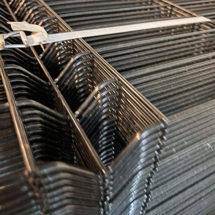 Nærbillede af stablede sorte ledninger fra 3D-panelhegn 4/4mm 173 cm SORT (125 m) + stolper 60×40 mm (240 cm) - Outlet-pakke, fastgjort med en hvid lynlås, der fremhæver den geometriske linjeføring og metallets glans.