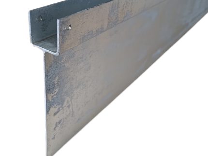Et nærbillede af en metallisk Z-formet inddækning lavet af varmgalvaniseret stål med en lodret forlængelse, der bruges i bygningskonstruktioner til vejrbeskyttelse og beskyttelse af tagkanter eller samlinger. Metaloverfladen er let struktureret og ser galvaniseret ud.