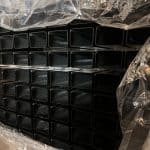 En stak 3D-panelhegn 4/4mm 173 cm SORT (125 m) med 60×40 mm (240 cm) stolper - Outlet-pakke, pænt arrangeret i rækker, er delvist dækket af klar plastfolie.