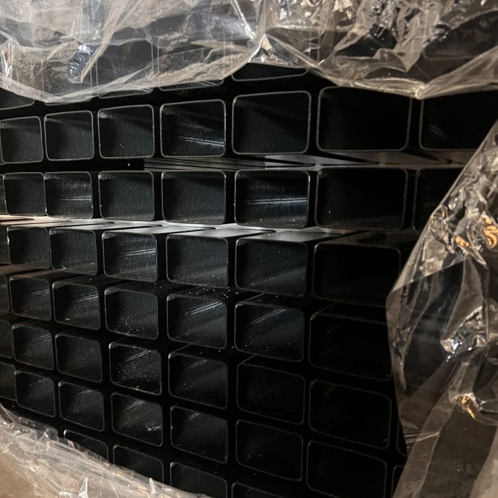 En stak 3D-panelhegn 4/4mm 173 cm SORT (125 m) med 60×40 mm (240 cm) stolper - Outlet-pakke, pænt arrangeret i rækker, er delvist dækket af klar plastfolie.