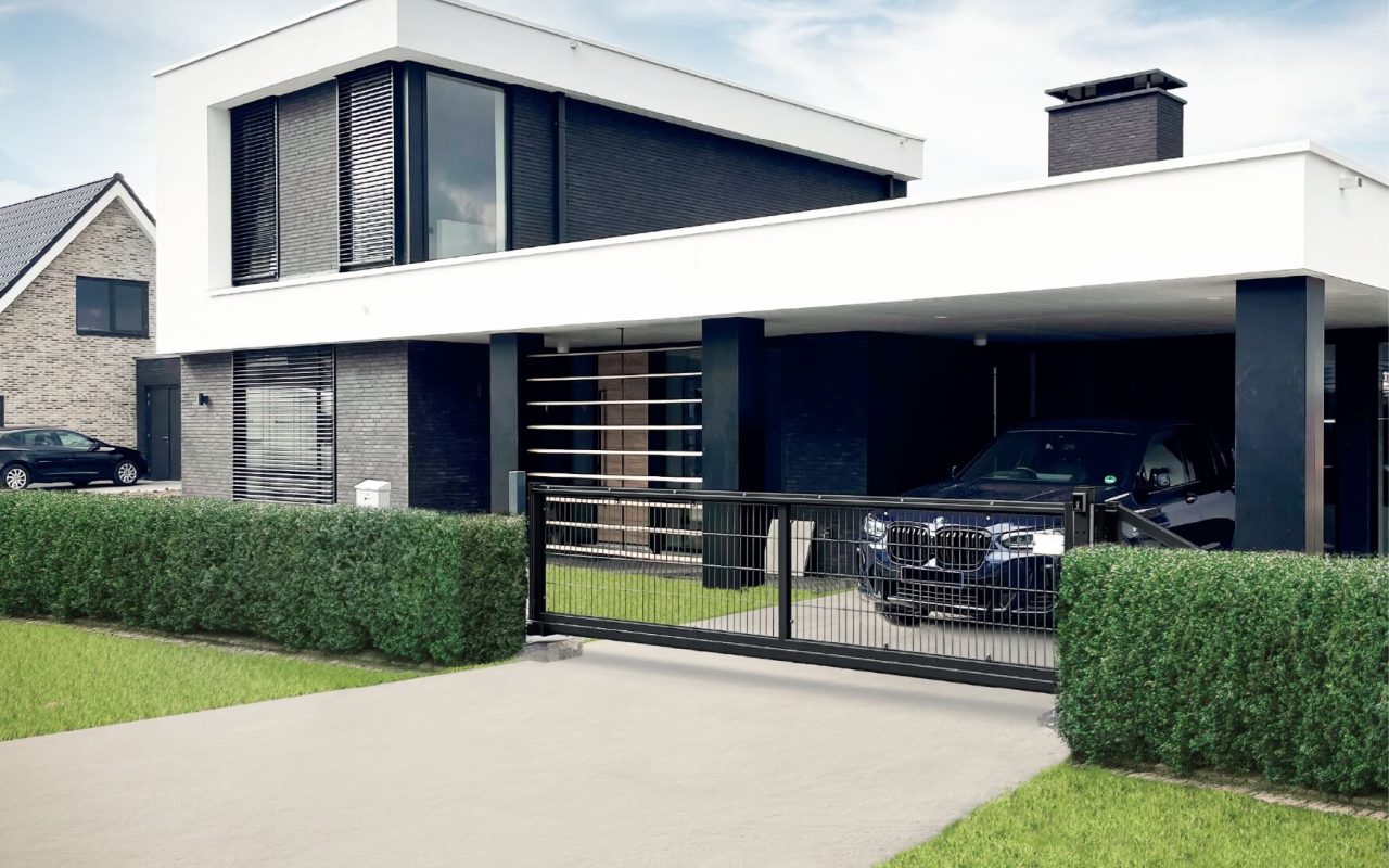 Moderne hus i to etager med sort og hvid facade (RAL 9005), store vinduer og indhegnet have. En sort bil er parkeret i den overdækkede indkørsel bag en HF Premium Skydeport - Frithængende med motor RAL 9005 Sort, omgivet af grønne hække.