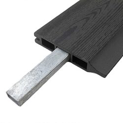 Nærbillede af et hult, mørkt kompositbræt med en Forstærkningsprofil til 25 mm kompositbrædder - varmgalvaniseret stål 15x28 mm delvist indsat i en af dets rektangulære indre kanaler.