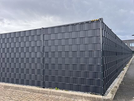 Højt 2D panelhegn i antracit med afskærmningsbånd, monteret på VAP-stolper med skjult fastgørelse og VAP-hjørnestolpe i hjørnet