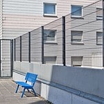 Panelhegn med låge monteret på støttemur, hvor stolperne er fastgjort med fodplader