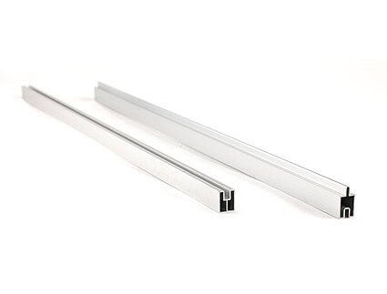 To sølvfarvede aluminiumskanaler med riller, der ligger parallelt på en hvid baggrund.