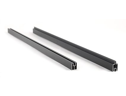 To sorte lineære stænger af metal eller plast med rillede kanaler på tværs af deres længde, placeret parallelt med hinanden på en hvid baggrund.