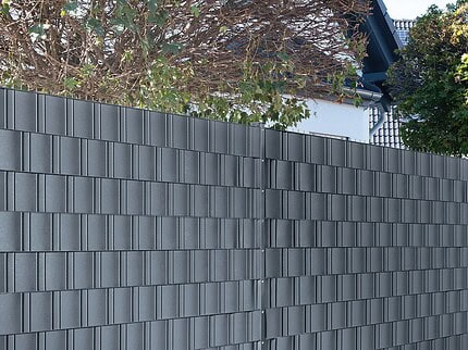 Antracitgrå POLYFIX afskærmningsbånd flettet ind i 2D panelhegn langs fortov