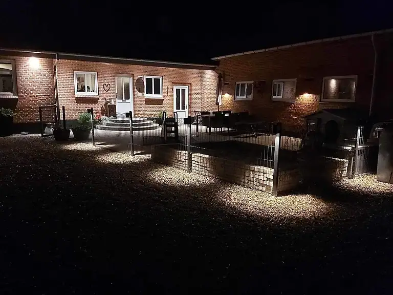 Gårdsplads med 3D-panelhegn og lys i stolperne efter mørkets frembrud