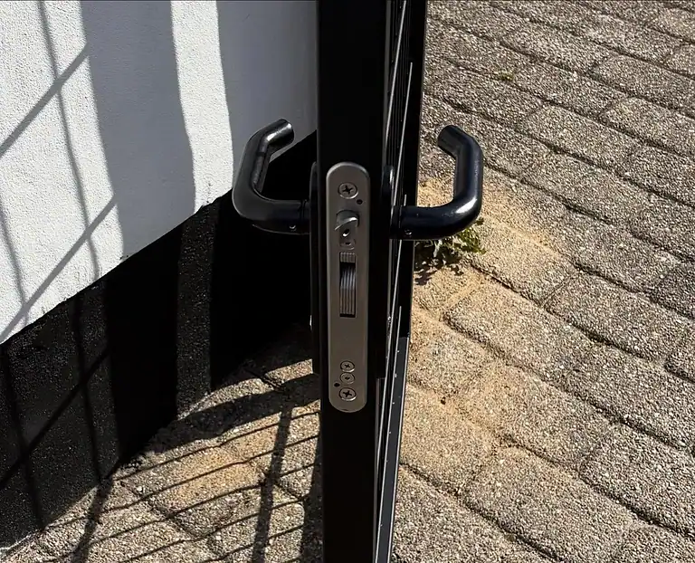 Nærbillede af lågens sorte håndtag og lås