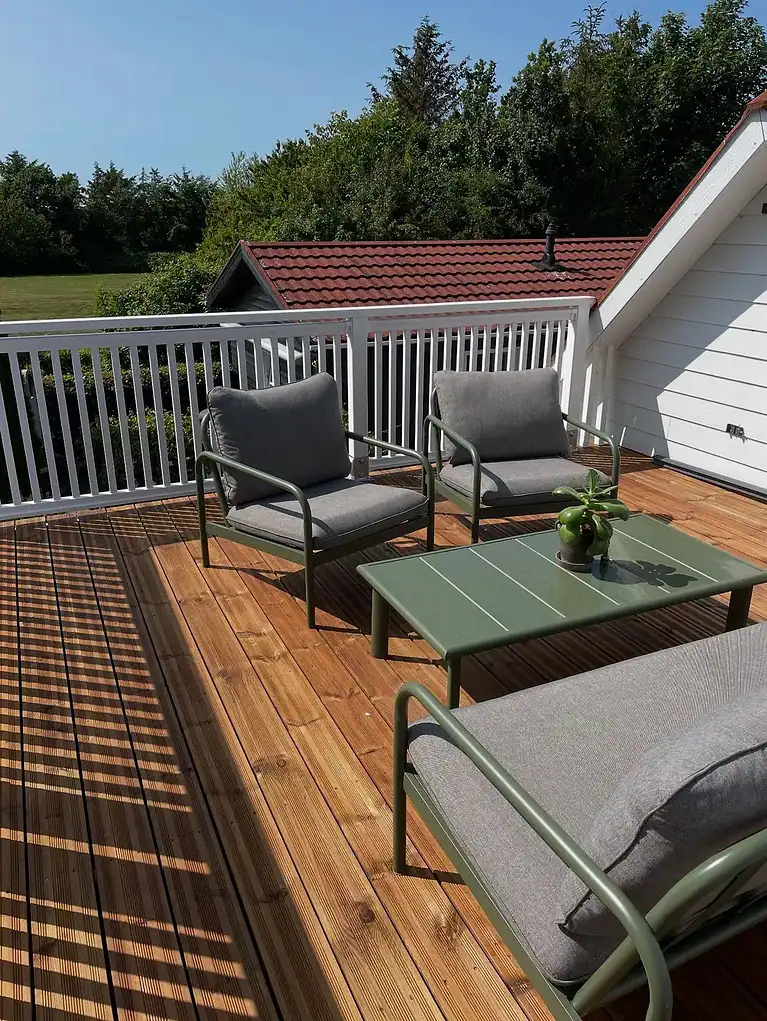 Træterrasse med hvidt rækværk og loungemøbler