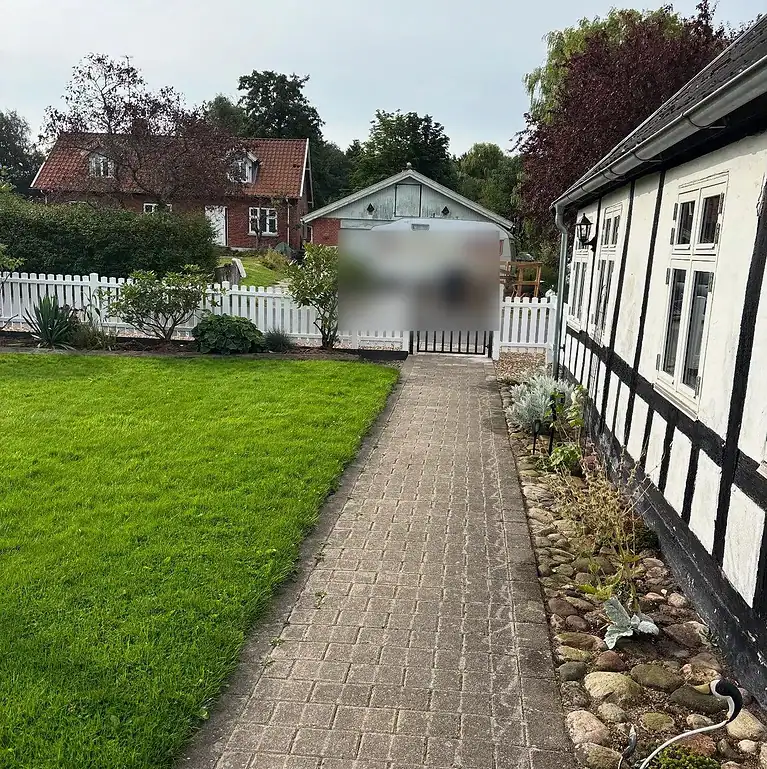 Hvidt stakit og havelåge ved en havegang
