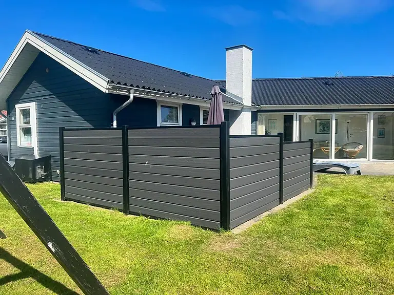 Komposithegn i antracit med sorte stolper ved et sommerhus