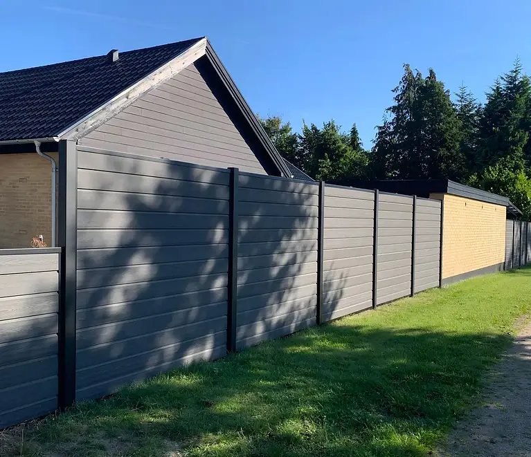 Komposithegn i 180 cm med sorte stålstolper ved huset