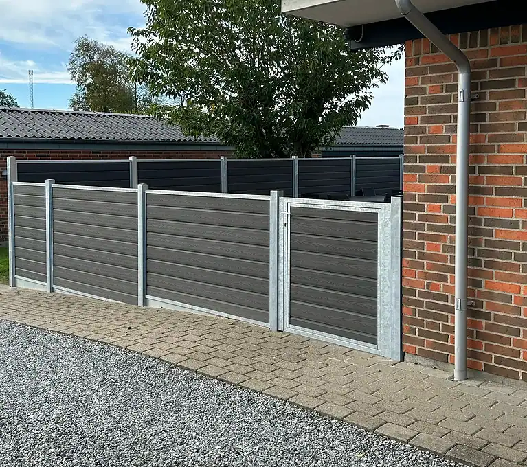 Komposithegn langs en flisegang ved huset