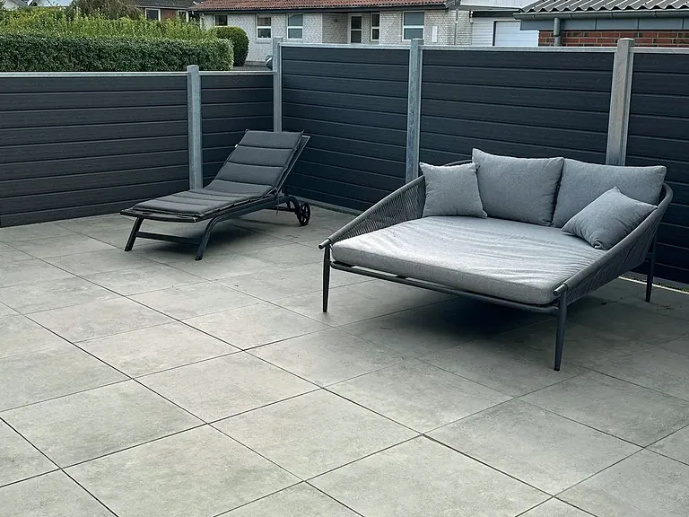 Ny terrasse med loungemøbler bag komposithegnet
