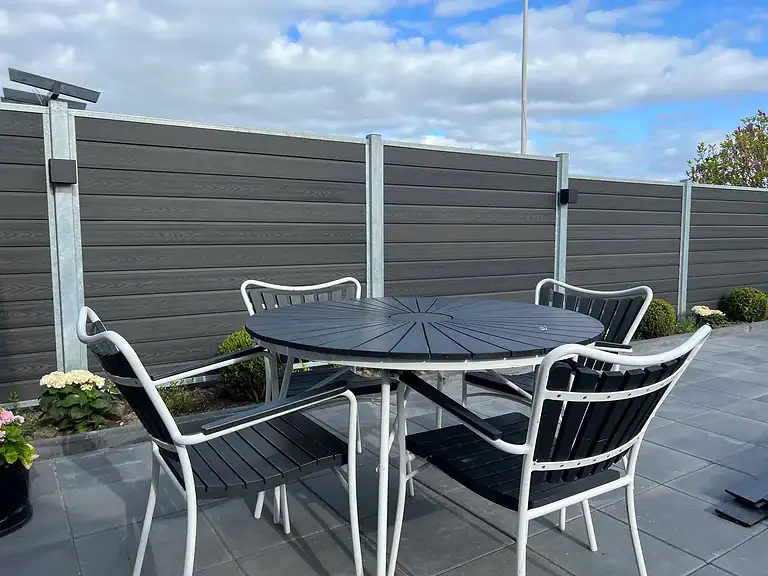Terrasse med havemøbler omgivet af komposithegn