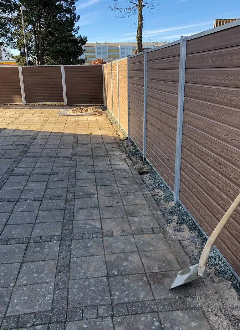 Brunt komposithegn med varmgalvaniserede stolper set langs hegnet