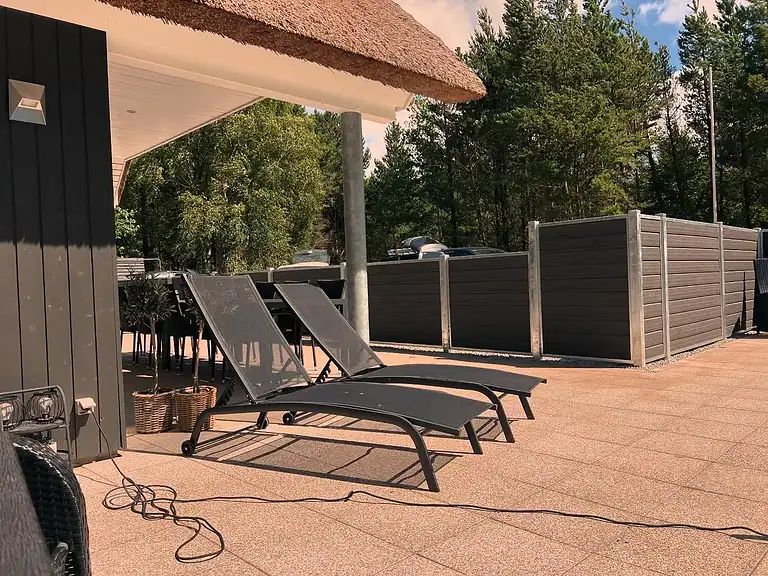 Liggestole på terrassen omgivet af komposithegn