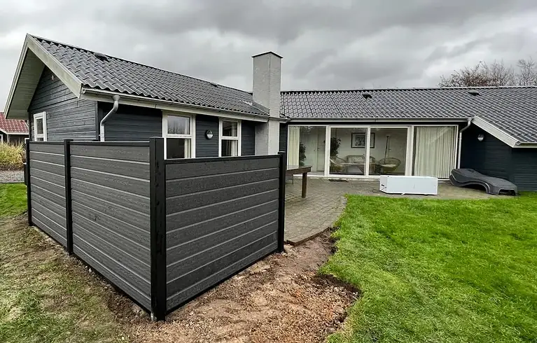 Komposithegn med sorte stolper ved et sommerhus