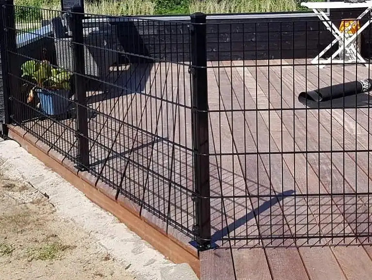 Sort 2D-panelhegn om en træterrasse ved sommerhuset